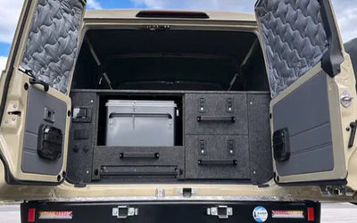 Back of a beige off-road vehicle with open cargo doors on a cloudy day showcasing a premium drawer system
